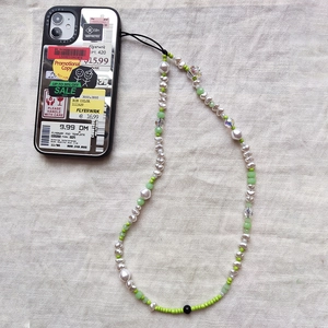 Dettaglio custodia a specchio argento con etichette vintage e cordino in perline