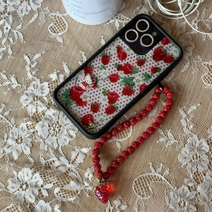 Detail of beaded phone strap with strawberry charm on a rhinestone floral phone case