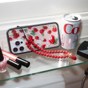 Detail of red berry pattern phone case with beaded wrist strap and heart pendant