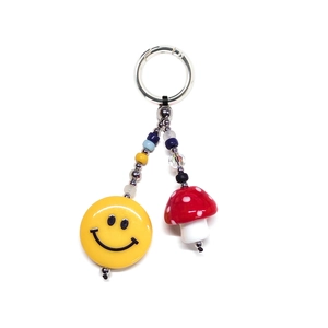 Detail von bunter Perlenkette mit gelbem Smiley und rotem Pilzanhänger für Taschen