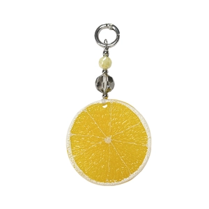 Detail of a realistic resin orange slice pendant with yellow frosted beads and silver clasp