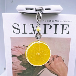 Detail of yellow lemon charm and faceted beads on a phone case with silver clasp