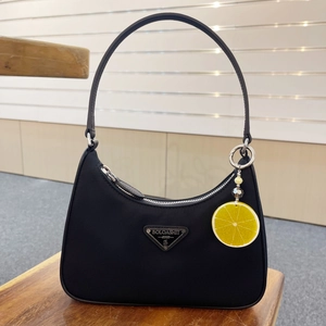 Close-up of black nylon hobo bag with metal logo plate and yellow lemon slice keychain