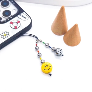 Détail du bijou de téléphone perlé avec perles smiley jaunes et breloque dé métallique