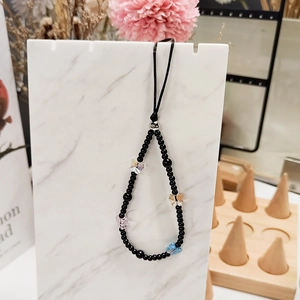 Handmade beaded phone strap with colorful acrylic butterflies on a marble stand