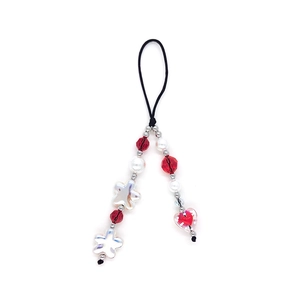 Detail of beaded phone strap with red faceted beads, pearls, and transparent heart pendant