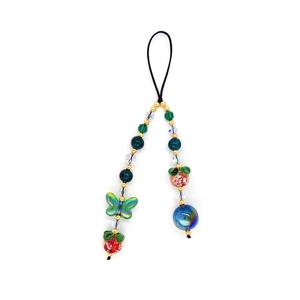 Detail of colorful beaded phone strap with green butterfly and red strawberry charms