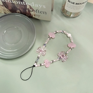 Chic pink beaded phone strap with heart and bow charms on a stylish lifestyle background