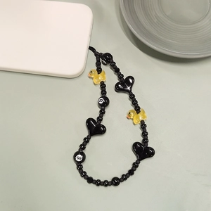 Beaded phone strap with black hearts and yellow duck charm on a white phone case