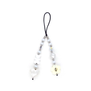 Detail of beaded phone strap with white bear, heart, and flower charms on white background