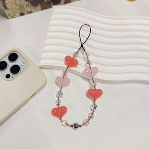 Pink heart-shaped acrylic beaded phone charm with crystal accents on a white board