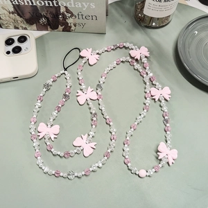 Bijou de téléphone perles avec nœuds roses et perles blanches sur bureau vert