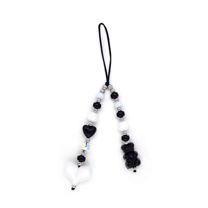 Detail view of monochrome heart beads and black bear pendant on mobile phone strap