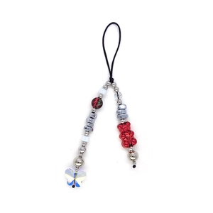 Detail of beaded phone strap featuring a red gummy bear and iridescent butterfly charms