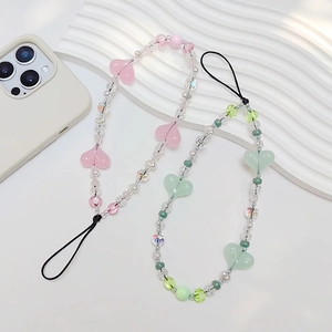 Close-up of beaded phone charms with acrylic heart pendants in pink and green colors