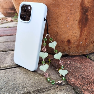 Handmade beaded phone charm with light green acrylic hearts and crystal beads on a case