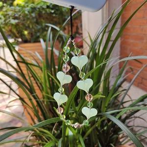 Beaded phone charm with light green hearts and crystal beads on a blue phone case