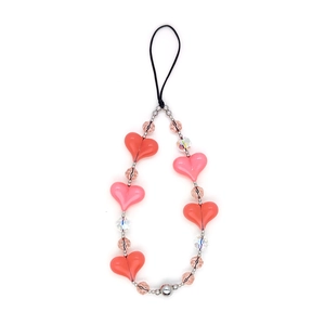 Close-up of pink heart-shaped acrylic beads and silver accents on a phone charm strap
