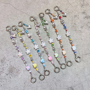 Handmade colorful beaded phone charms with stars, hearts and flowers on grey surface