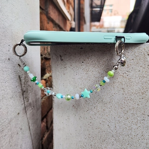 Mint green silicone phone case with colorful star and heart beaded charm on stone