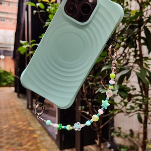 Mint green ripple phone case with star heart beaded strap on blurred nature background