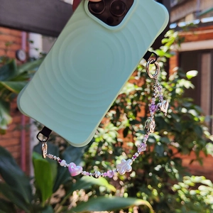 Mint green wave phone case with colorful heart beaded strap held in a hand