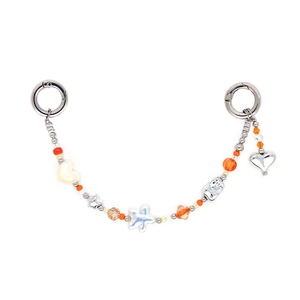 Detail of colorful beaded charm with orange beads, white hearts and silver metal clasps