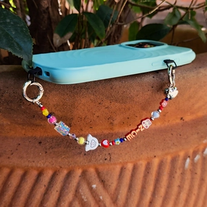 Colorful beaded phone strap with NICE letters and heart charm on a blue case