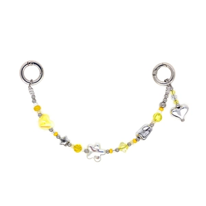 Close-up of vibrant yellow beaded chain with silver heart and star charms for bags