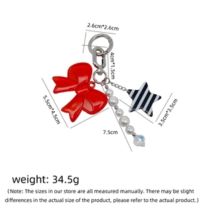 Detail of red bow keychain with white pearls, star pendant and clear crystal charm