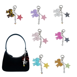 Detail of colorful bow and star bag charms with pearls shown on a black crescent bag