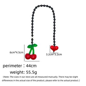 Detail view of 44cm black beaded bag chain with cherry and red heart shaped charms