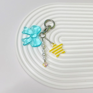 Close-up of sky blue acrylic bow and faux pearl chain pendant with yellow star detail