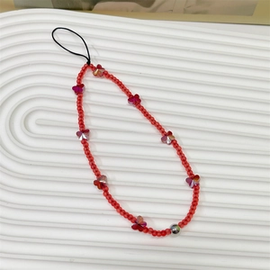 Macro detail of red beaded phone strap featuring frosted beads and butterfly charms
