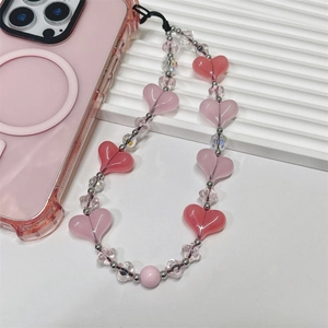 Detail of pink heart-shaped beaded phone charm with acrylic beads on a mobile case
