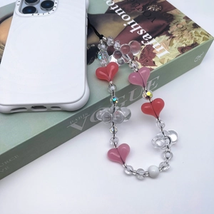 Pink and white beaded heart phone strap on a magazine with a white mobile case
