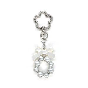 Détail du porte-clés avec nœud en satin blanc et fermoir en argent en forme de fleur