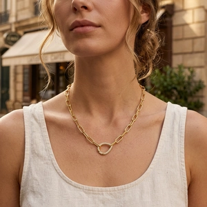 Detailed view of golden paperclip chain necklace with zircon-encrusted D-buckle closure