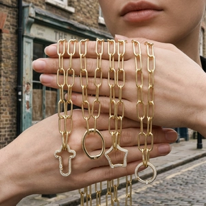 Detail of chunky gold link chains with pavé diamond cross, star, and circle carabiner clasps