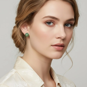 Elegant close-up of retro green round stud earrings with gold bead on silk shirt