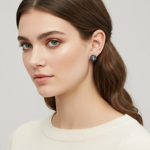 Detail of round stud earring with blue marble texture and gold bead on ear lobe
