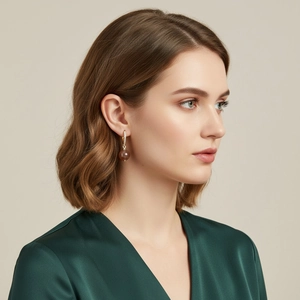 Detail of elegant gold-plated earrings with reddish-brown gemstone on female model