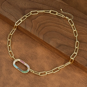 Detailed macro of gold paperclip chain featuring multi-color zircon pavé clasp