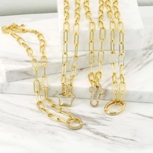 Detailed view of golden paperclip chains with star and cross charms set with zircons