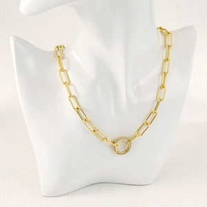 Close-up of golden paperclip necklace with a sparkling diamond-encrusted round clasp