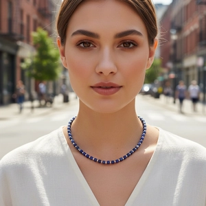 Close-up of square cut blue lapis lazuli beads necklace worn by model on city street
