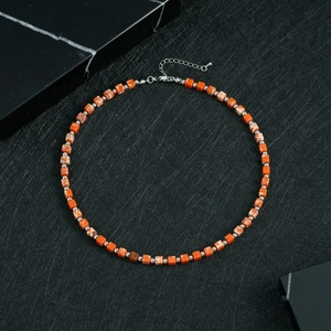 Detail of square orange stone beads and silver spacers on a minimalist beaded necklace