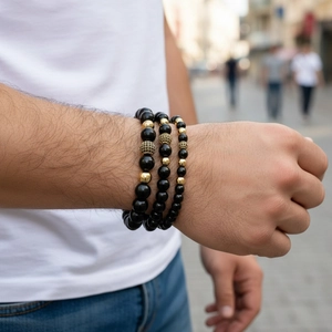 Close-up of men's beaded bracelet set featuring black stones and gold micro-pave accents