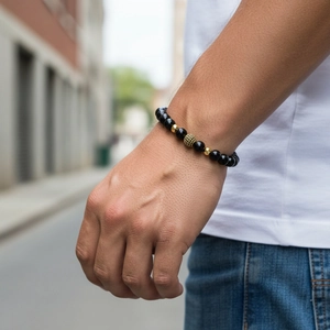 Close-up of matte black beads bracelet with gold crown accents on male model wrist