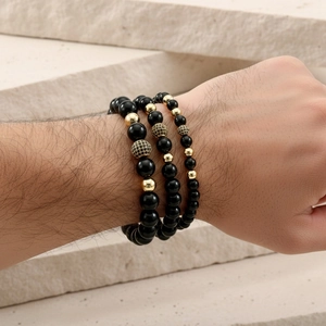 Detailed shot of men's triple-layered black onyx and gold beaded crown bracelet set